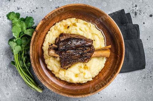 Preview: Braised lamb shank on the mashed potato in a plate. Gray background. Top view