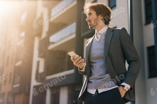 Preview: Below view of young businessman using mobile phone in the city.