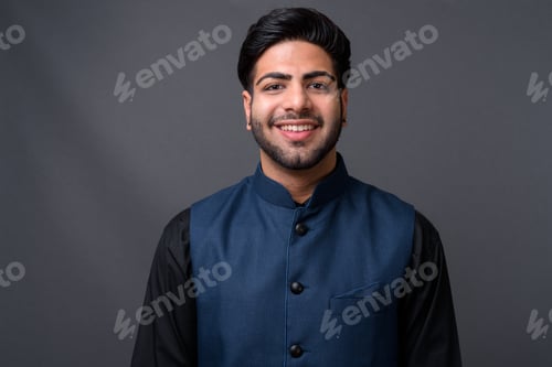 Preview: Young handsome Indian businessman against gray background