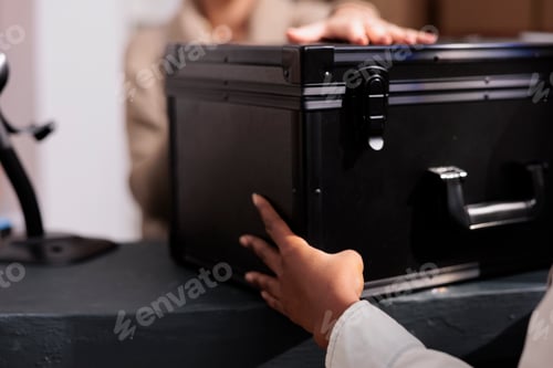 Preview: Stockroom employee giving colleague black case at reception desk
