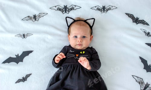 Preview: Little girl in a black cat costume on a background of bats, Halloween idea for celebrating Halloween
