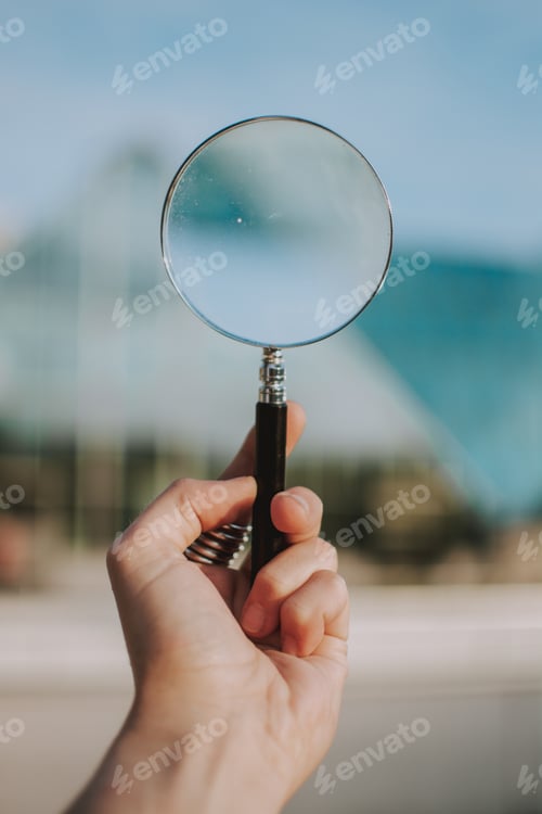 Preview: Vertical selective shot of a person holding a clear magnifying glass