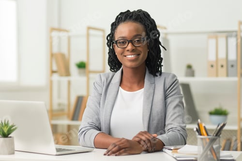 Preview: Afro Business Lady Smiling At Camera Sitting At Workplace