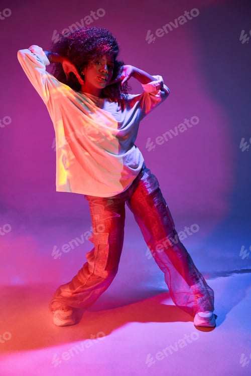 Preview: Stylish black woman dancing in neon lights and touching hair