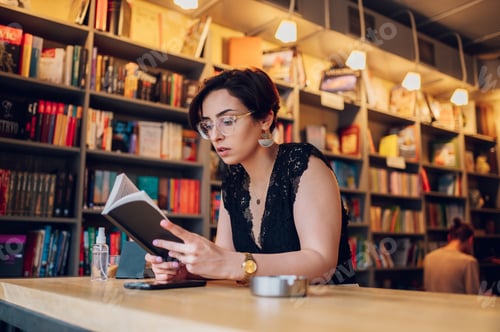 Preview: Woman reading a book while relaxing in the cafe or a bookstore