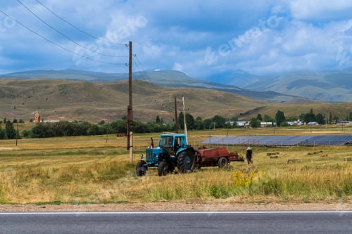 Preview: Tracktor collecting hay in mountain meadow at springtime