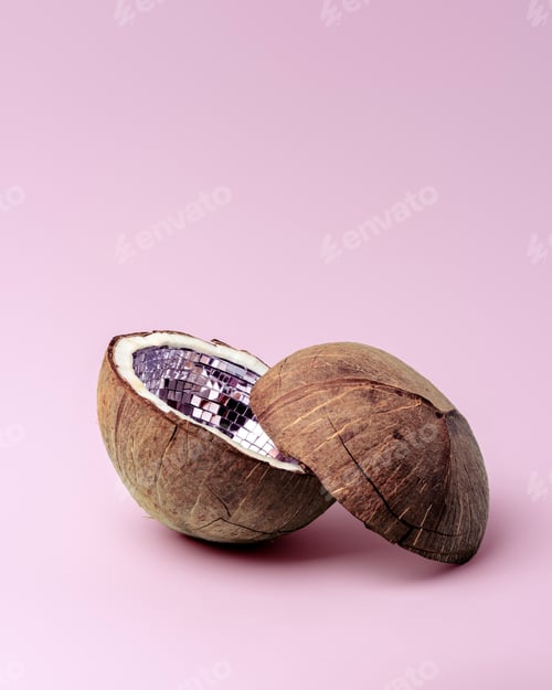 Preview: Open coconut shell with bright disco mirror tiles on soft pink background in minimal studio setup.