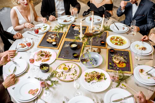Preview: Elegantly dressed people having a festive dinner indoors