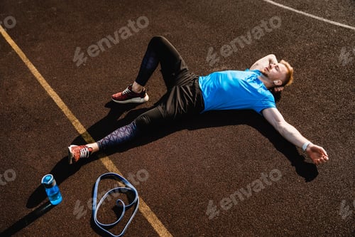 Preview: Young male athlete resting after training in sporty clothes on sporting ground