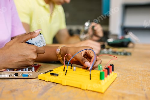 Close up female student hands creating electronic circuits and robotics at class