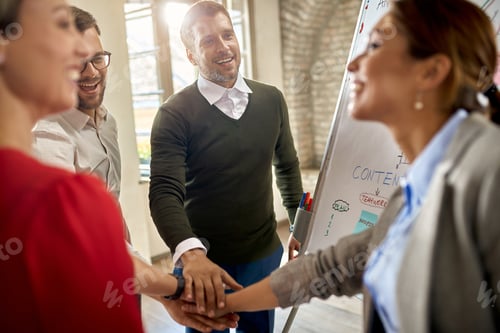 Preview: Happy business team gathering hands in unity after successful presentation.