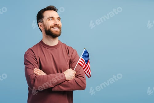 Preview: Confident smiling man holding American flag isolated on blue background