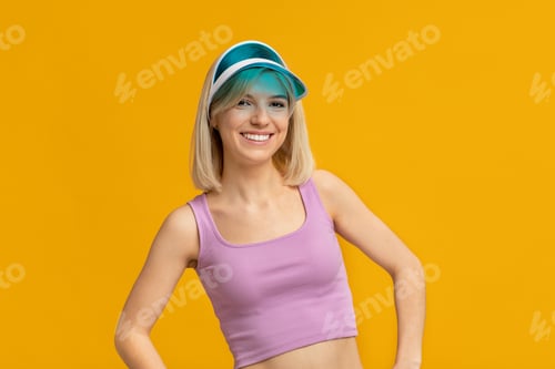 Preview: Happy woman in colorful summer hat posing on yellow studio background, smiling and looking at camera