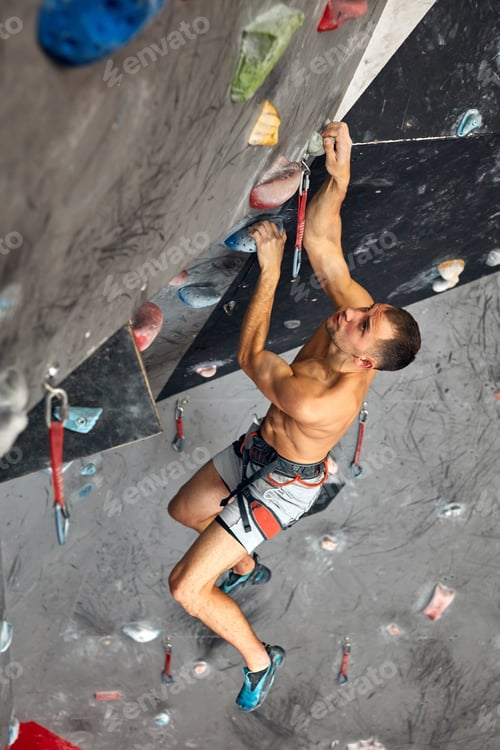 Preview: Male professional climber at indoor workout at bouldering centre.