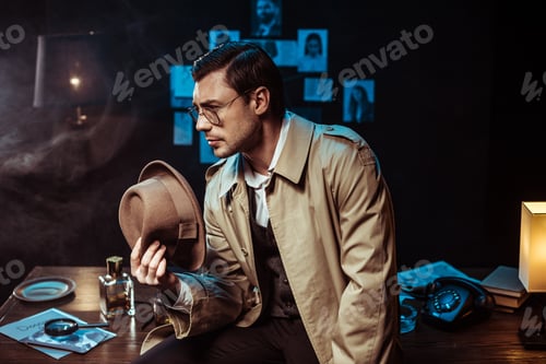 Preview: Pensive detective in glasses and trench coat sitting on table and holding hat