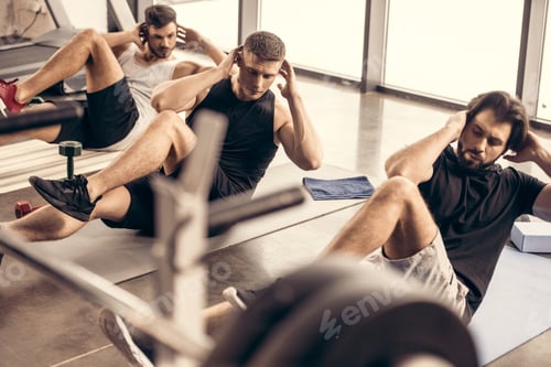 Preview: handsome sportive friends doing sit ups together in gym