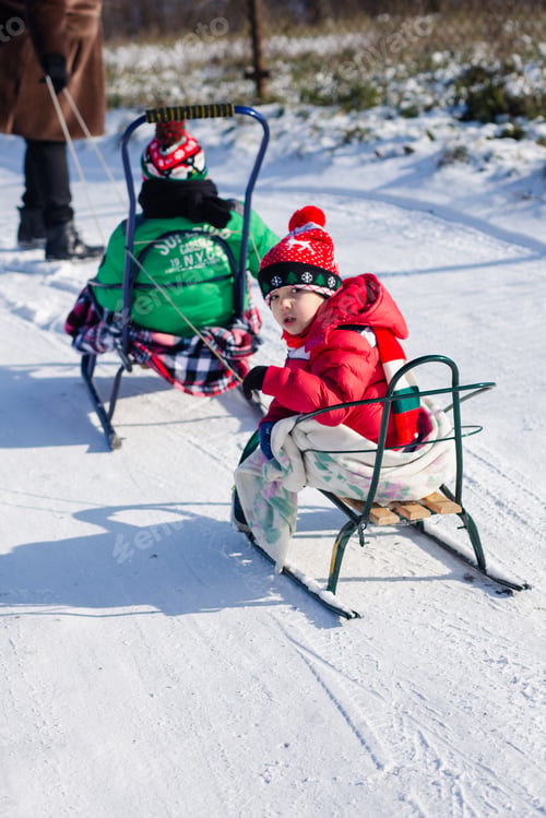 Preview: Children sledding on the snowy street . Winter walking