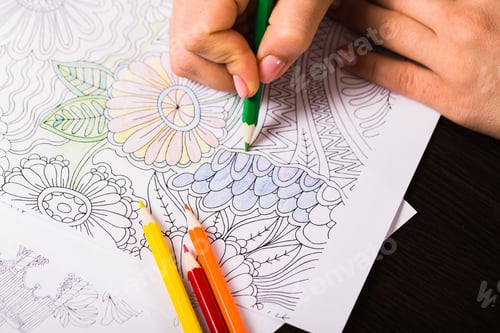 Preview: Girl paints a coloring book for adults with crayons