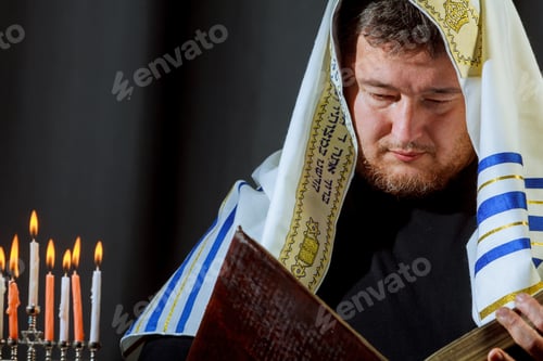 Preview: Jewish candle lights male hand lighting candles in menorah on table served for Hanukkah