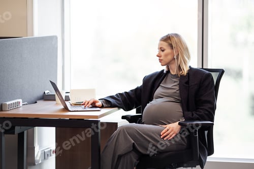 Preview: Confident pregnant female executive efficiently works on her computer in the office, seated at her
