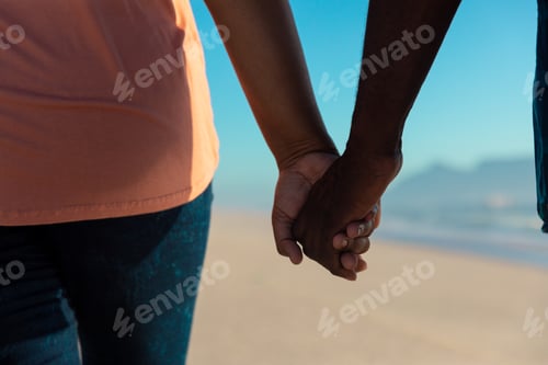 Preview: Midsection of african american senior couple holding hands at beach
