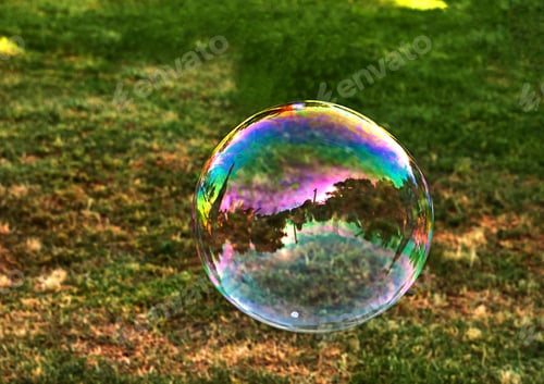 Preview: A soap bubble flies against the background of green grass.