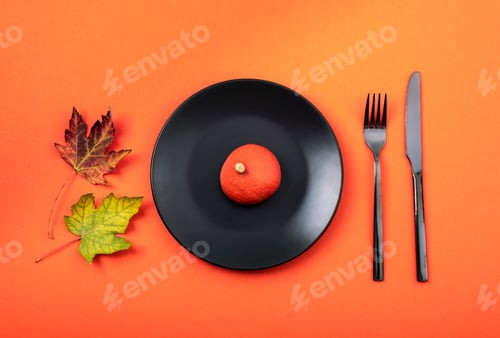 Preview: Autumn table place setting with black plate with pumpkin on orange background. Thanksgiving