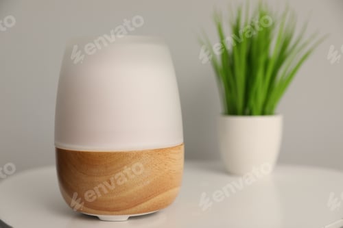 Preview: Modern aroma lamp and floral decor on white table indoors, closeup