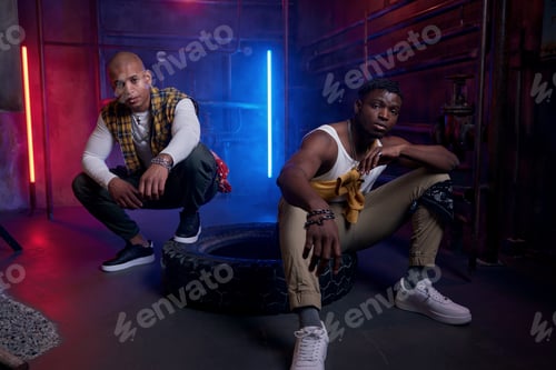 Preview: Two young drug dealers with serious faces posing for camera in neon light