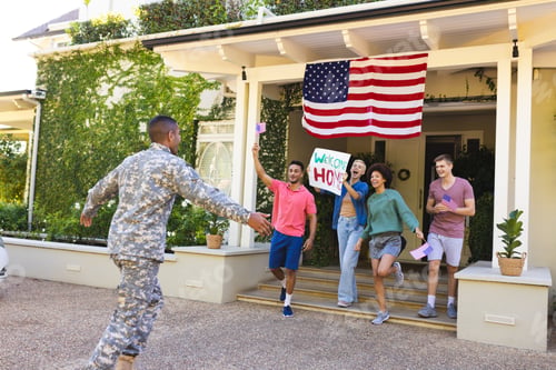 Preview: Happy diverse group of friends greeting biracial male american soldier outside the house