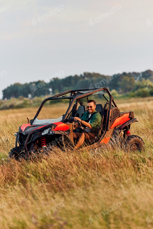 Preview: A smiling man with sunglasses driving a rented quad bike off-road.