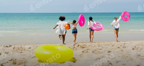 Preview: Wide shot of back of teen girls hold swimming ring and balls also run to the sea and they look happy