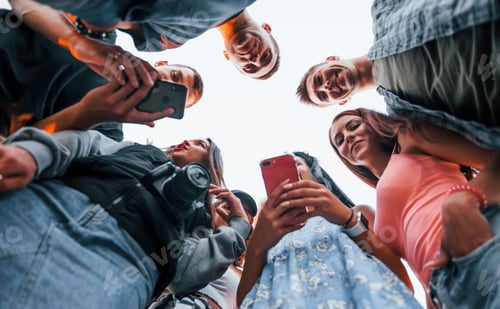 Preview: view from below. With phone. Group of young cheerful friends having fun together. Party outdoors