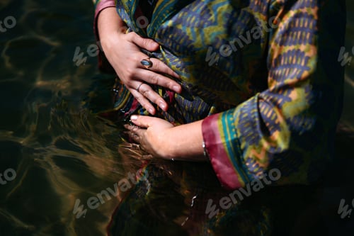 Preview: Woman wearing a fabric silk bathrobe half submerge in the water