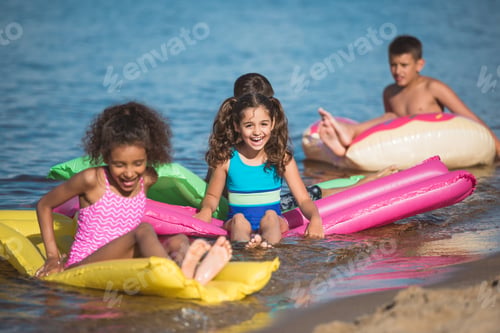 Preview: multiethnic little children swimming on colorful inflatable mattresses at sea together