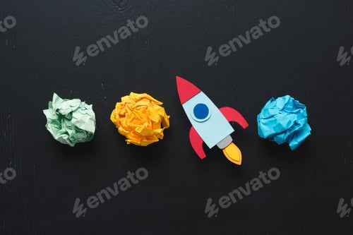 Preview: top view of cardboard rocket with crumpled paper balls on black background, setting goals concept
