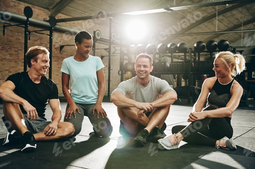 Preview: Smiling friends talking together on a gym floor after exercising