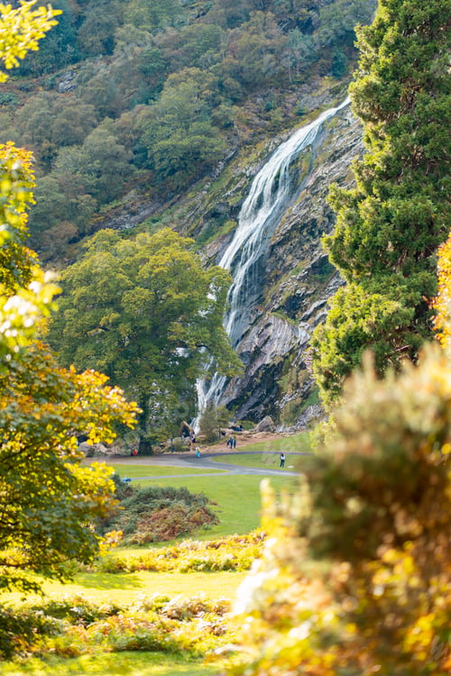 Preview: Beautiful shot of green trees and a waterfall descending on green hills on a sunny day