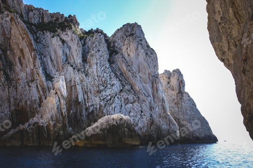 Preview: Ocean surrounded by the rocky cliffs gleaming under the blue sky - great for wallpapers
