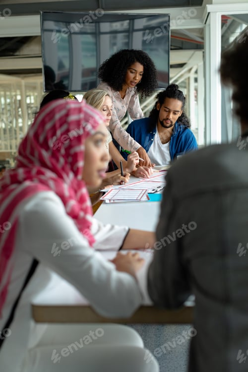 Preview: Diverse business people discussing together over documents at conference room in a modern office