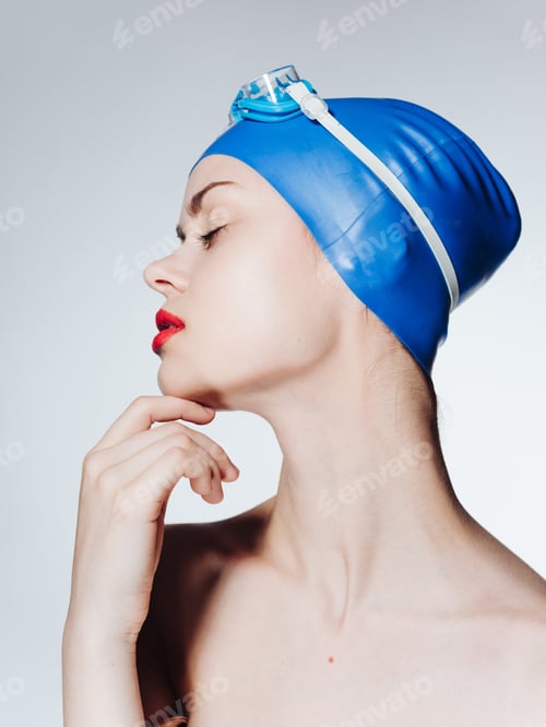 Preview: Side view of a beautiful woman in a blue swimming cap, naked shoulders