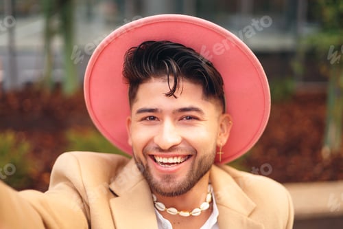 Preview: young hispanic man taking selfie in modern outdoors, camera pov