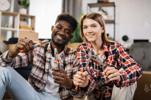 Preview: Multiracial couple holding repair instruments at home
