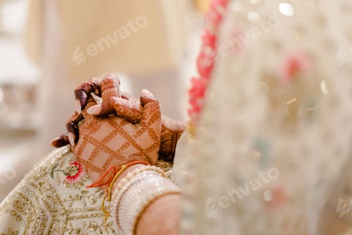 Preview: Hands of a newlywed Indian bride with nice henna design wearing a white bridal dress