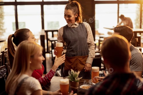 Preview: Happy waitress serving beer to group of friends in a bar.