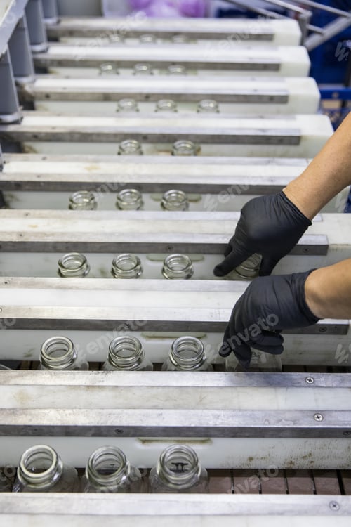 Preview: Vertical shot of glass bottles organized by a worker in recycling machinery