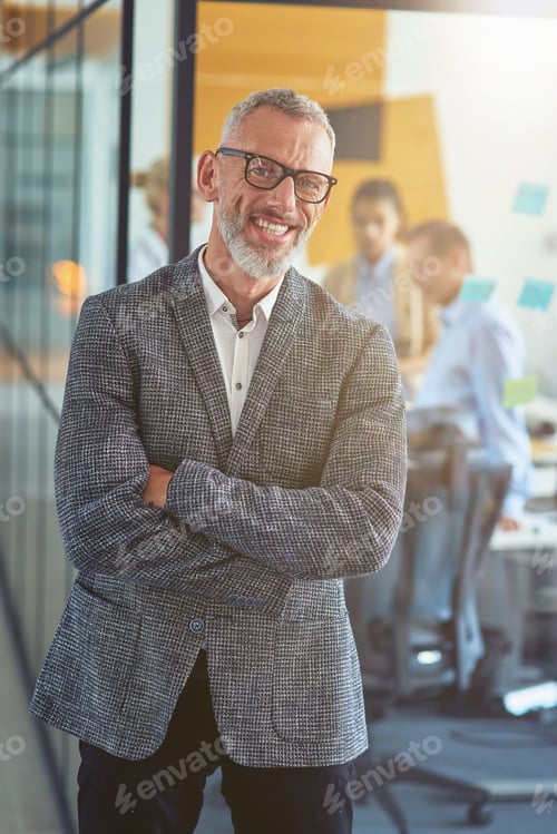 Preview: Vertical shot of a cheerful mature businessman in classic wear keeping arms crossed and smiling at