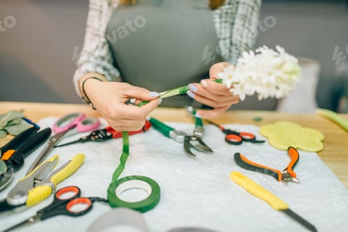 Preview: Female florist prepares rose bouquet at workplace