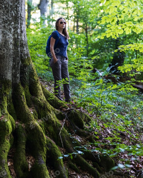 Preview: Young travel woman with backpack exploring woods in mountains in the morning