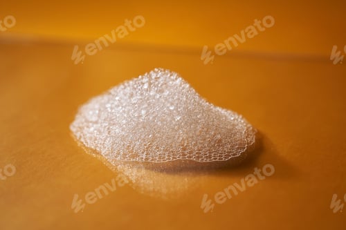 Preview: White foam from shampoo or shower gel on a bright yellow background.
